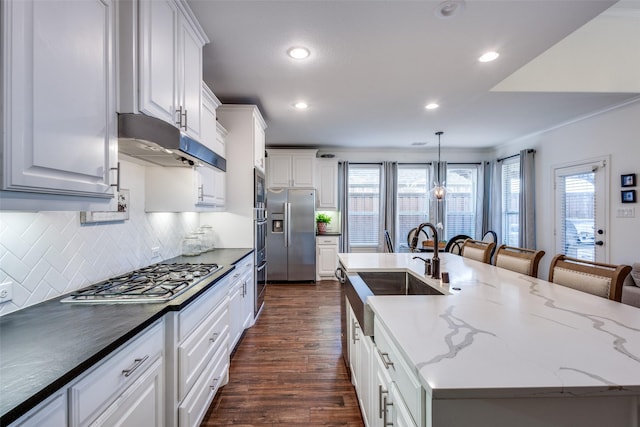 kitchen featuring white cabinets, a kitchen breakfast bar, hanging light fixtures, stainless steel appliances, and a spacious island