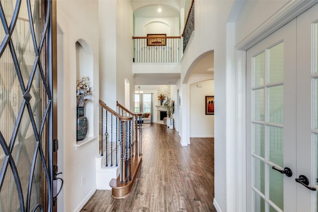 foyer entrance featuring french doors, a towering ceiling, and wood-type flooring