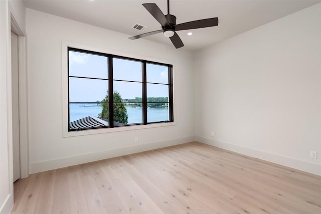 unfurnished room with a water view, ceiling fan, and light hardwood / wood-style floors