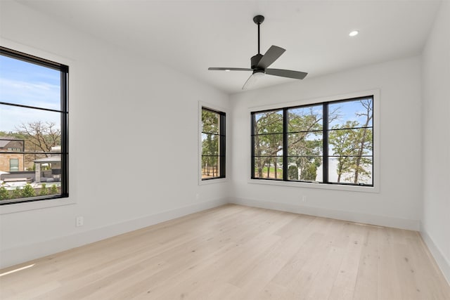 empty room with ceiling fan, plenty of natural light, and light hardwood / wood-style floors