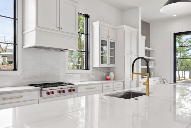 kitchen with sink, white cabinetry, light stone counters, decorative light fixtures, and stainless steel gas stovetop