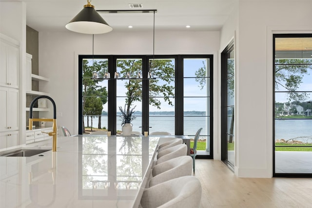 interior space with a water view, sink, and light hardwood / wood-style flooring