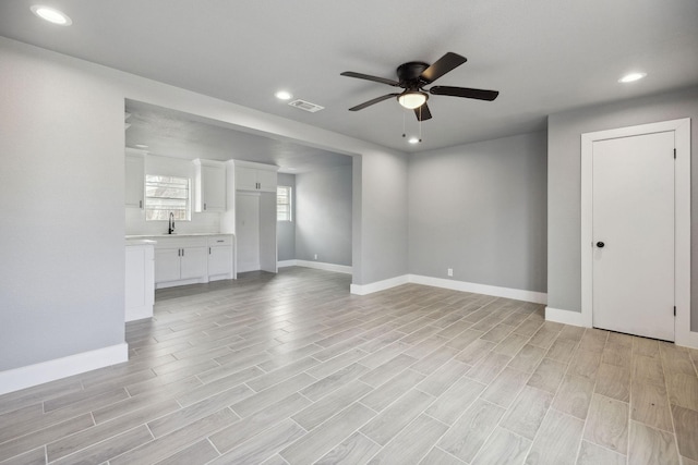 unfurnished living room with ceiling fan, sink, and light wood-type flooring