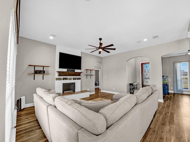 living room featuring wood-type flooring, a fireplace, and ceiling fan