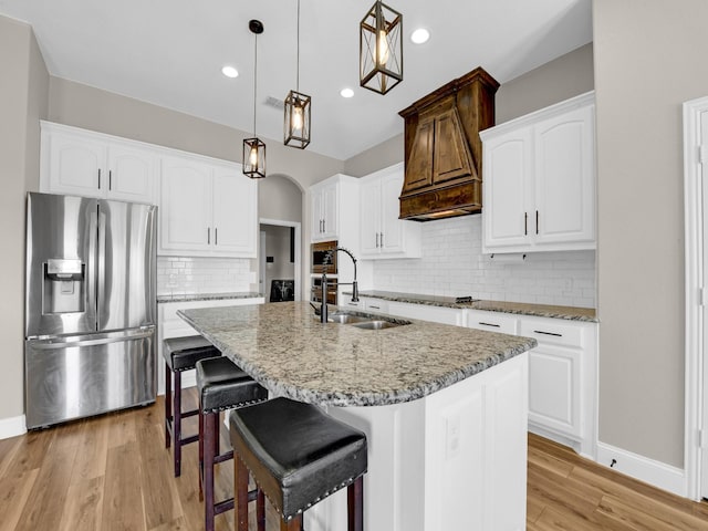 kitchen with pendant lighting, sink, stainless steel appliances, an island with sink, and white cabinets