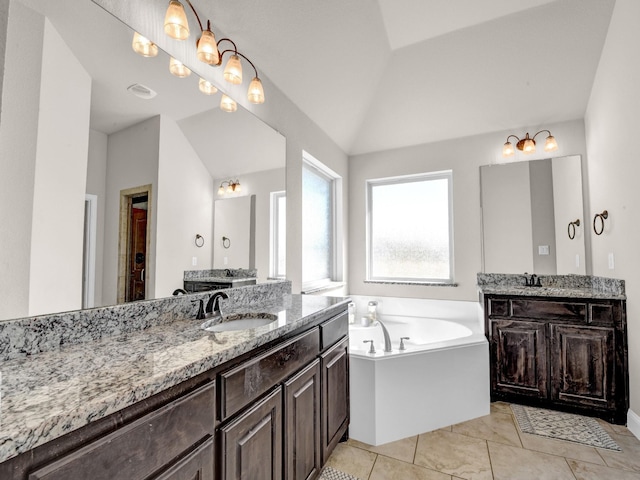 bathroom featuring tile patterned floors, vanity, a bathing tub, and vaulted ceiling