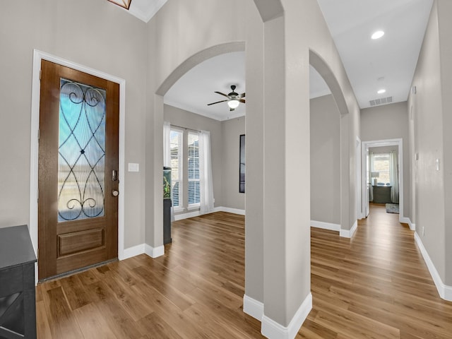 foyer with ceiling fan, ornamental molding, and light wood-type flooring