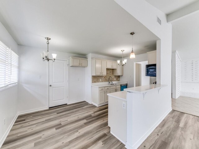 kitchen with pendant lighting, sink, kitchen peninsula, and a chandelier