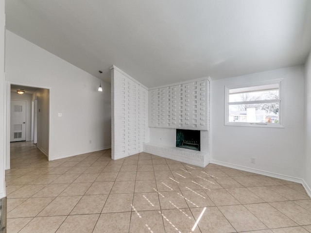 unfurnished living room with vaulted ceiling, a brick fireplace, and light tile patterned floors
