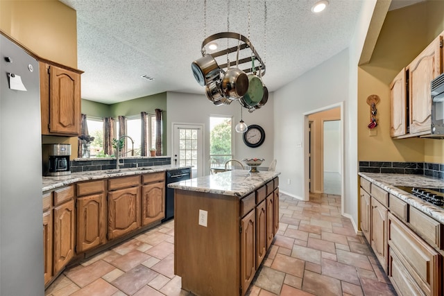 kitchen with sink, a center island, a textured ceiling, light stone countertops, and black appliances