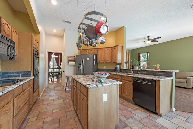 kitchen with a kitchen island, sink, ceiling fan, black appliances, and a textured ceiling