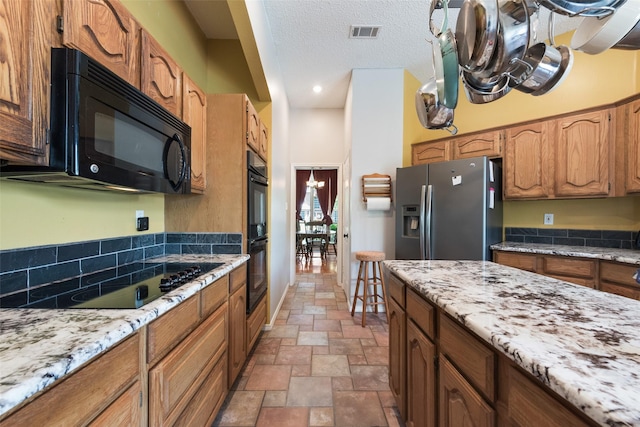 kitchen featuring light stone countertops, a textured ceiling, and black appliances