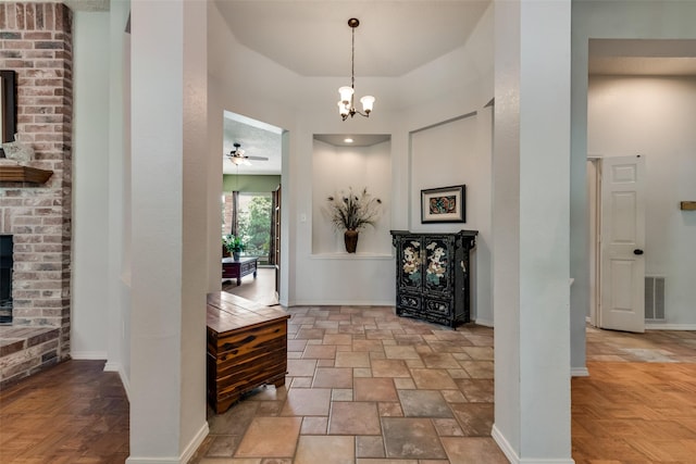 foyer entrance featuring ceiling fan with notable chandelier, a fireplace, and light parquet floors