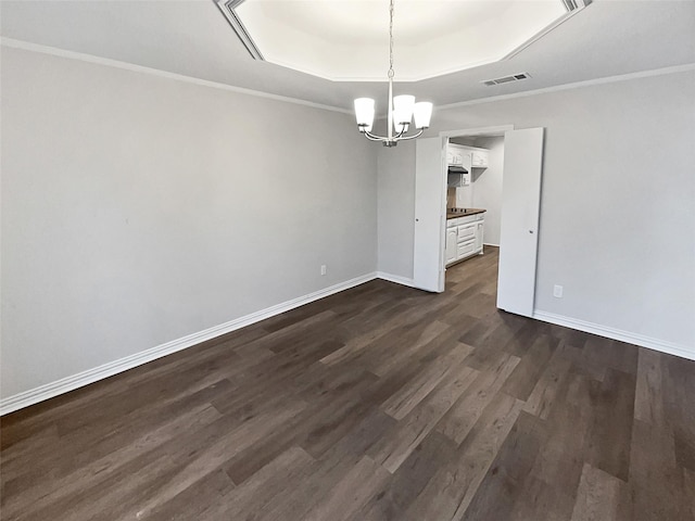 unfurnished dining area with dark hardwood / wood-style floors, ornamental molding, a tray ceiling, and an inviting chandelier