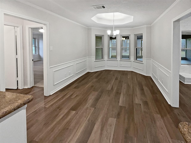 unfurnished dining area with ornamental molding, a notable chandelier, dark hardwood / wood-style flooring, and a tray ceiling