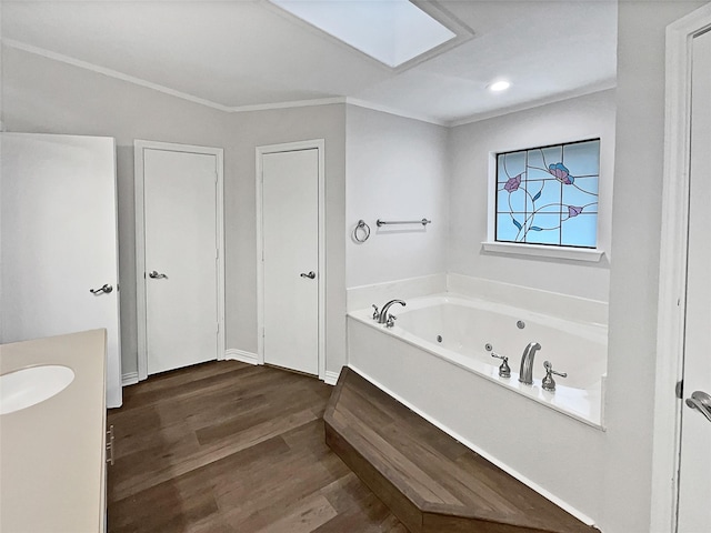 bathroom with a washtub, crown molding, hardwood / wood-style floors, a skylight, and vanity