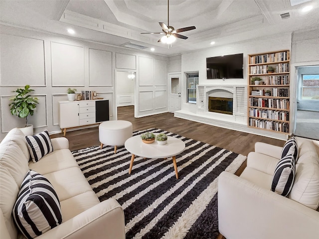 living room with a raised ceiling, ornamental molding, ceiling fan, and dark hardwood / wood-style flooring