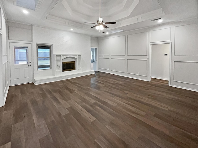 unfurnished living room with a tray ceiling, a fireplace, dark hardwood / wood-style floors, and ceiling fan