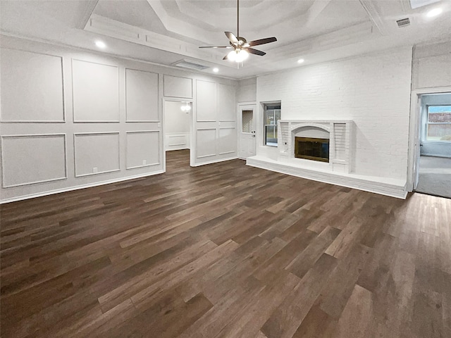 unfurnished living room with a brick fireplace, a tray ceiling, and dark hardwood / wood-style floors