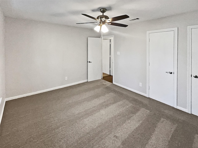 unfurnished bedroom with two closets, ceiling fan, and dark colored carpet