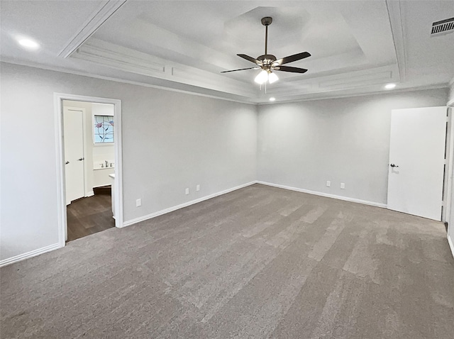 unfurnished room with crown molding, ceiling fan, a tray ceiling, and dark carpet