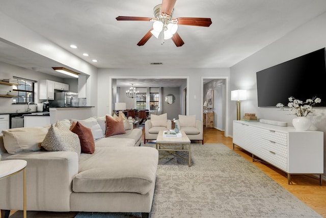 living room featuring sink, ceiling fan with notable chandelier, and light hardwood / wood-style flooring