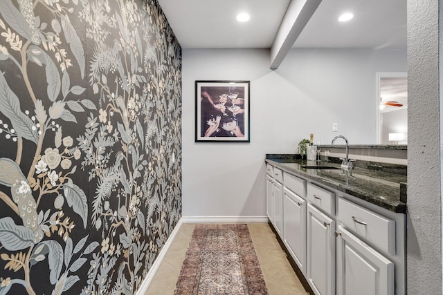 interior space featuring sink, dark stone counters, white cabinets, and light tile patterned flooring