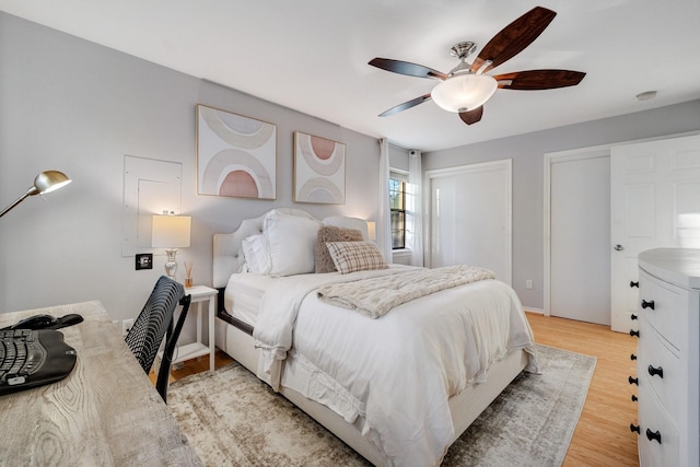 bedroom featuring two closets, ceiling fan, and light wood-type flooring