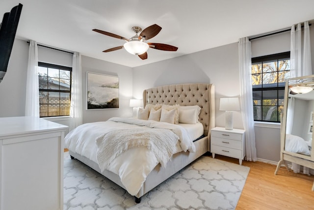 bedroom with multiple windows, light hardwood / wood-style flooring, and ceiling fan