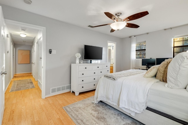 bedroom with ceiling fan, connected bathroom, and light wood-type flooring