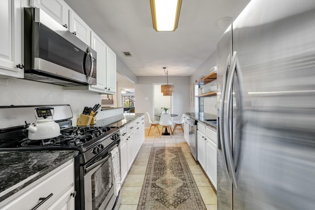 kitchen featuring light tile patterned floors, white cabinetry, hanging light fixtures, stainless steel appliances, and tasteful backsplash