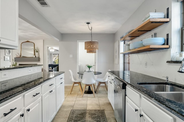 kitchen with sink, white cabinetry, dark stone countertops, stainless steel dishwasher, and backsplash