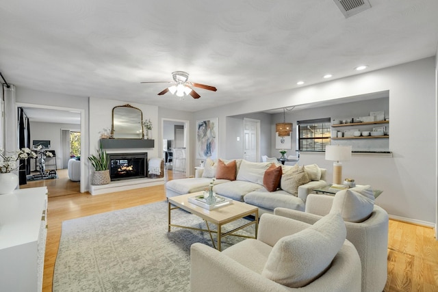 living room with a multi sided fireplace, plenty of natural light, and light wood-type flooring