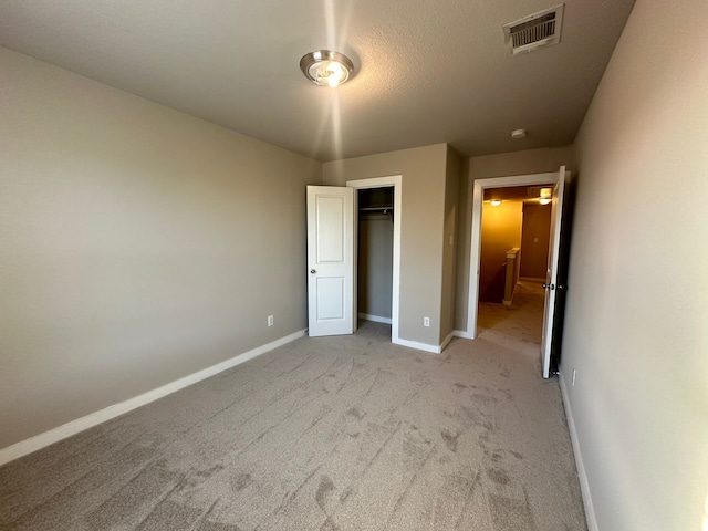 unfurnished bedroom featuring a closet and light carpet