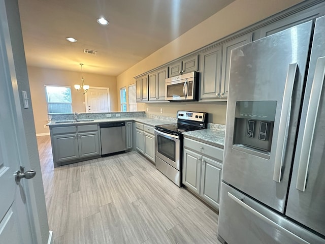 kitchen featuring sink, gray cabinetry, decorative light fixtures, kitchen peninsula, and stainless steel appliances