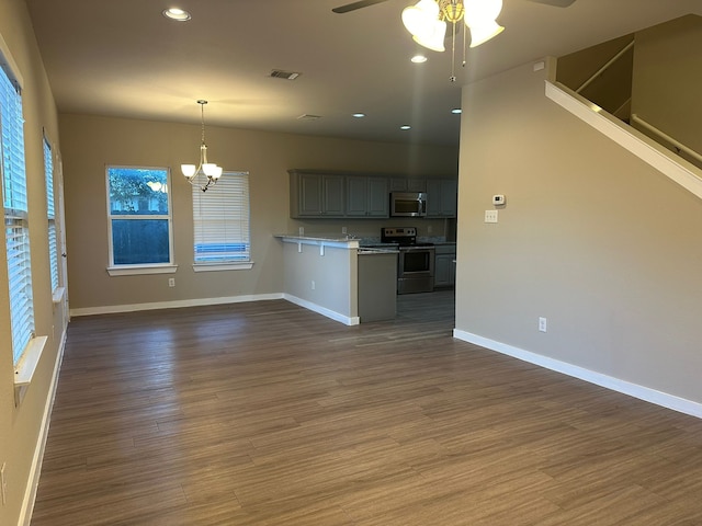 kitchen with decorative light fixtures, dark hardwood / wood-style flooring, gray cabinets, stainless steel appliances, and ceiling fan with notable chandelier