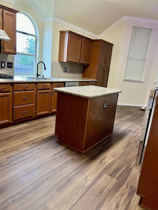 kitchen featuring crown molding, a center island, a sink, and wood finished floors