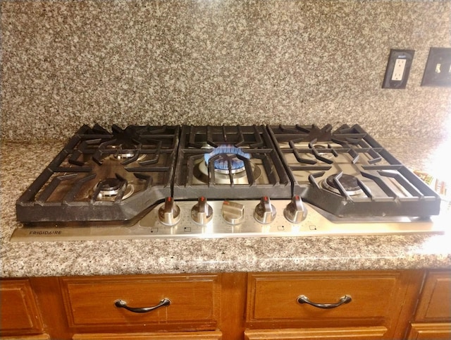 room details with brown cabinetry and stainless steel gas stovetop