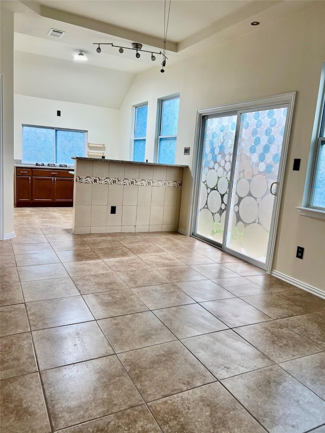 kitchen featuring a healthy amount of sunlight, vaulted ceiling, visible vents, and light tile patterned floors