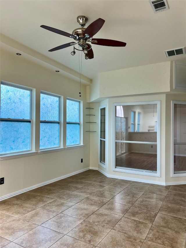 tiled empty room featuring built in shelves, visible vents, and baseboards