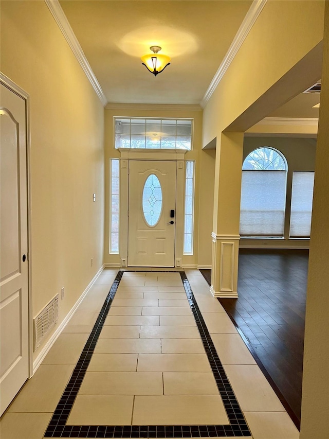 entrance foyer with baseboards, visible vents, crown molding, and tile patterned floors