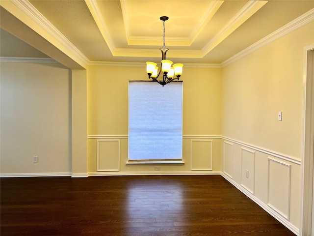 spare room with a tray ceiling, crown molding, dark wood finished floors, a notable chandelier, and a decorative wall