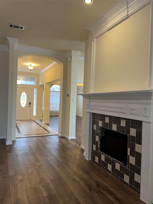 living area with arched walkways, visible vents, baseboards, ornamental molding, and dark wood finished floors