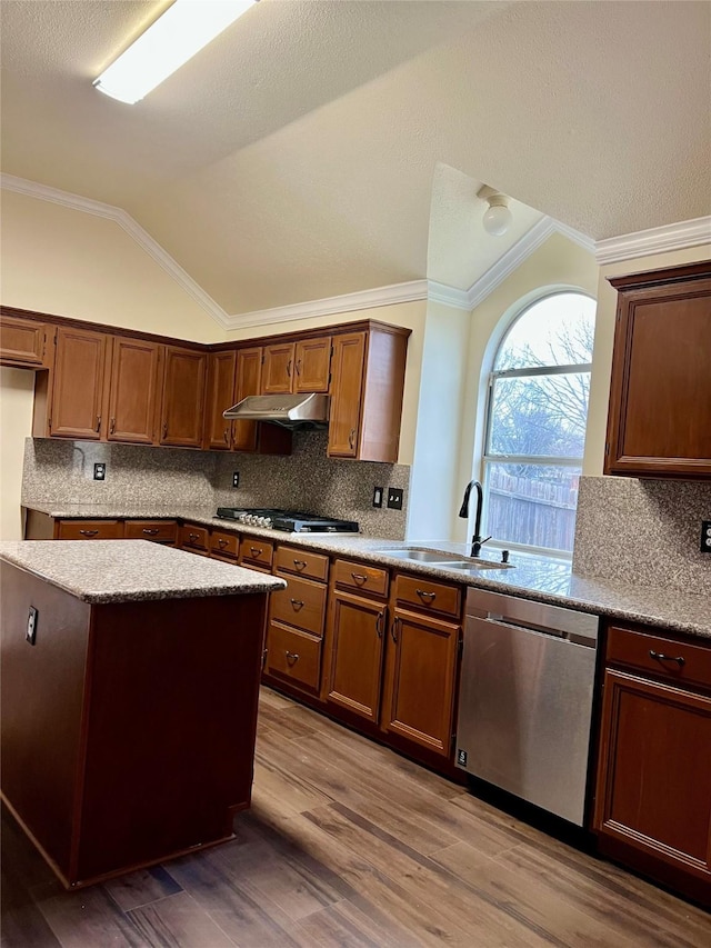 kitchen featuring lofted ceiling, stainless steel dishwasher, under cabinet range hood, gas cooktop, and a sink