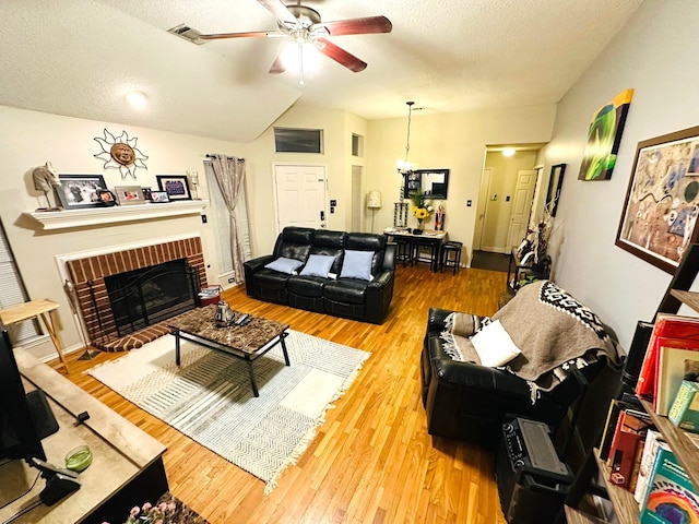 living room featuring ceiling fan, hardwood / wood-style floors, a fireplace, and a textured ceiling