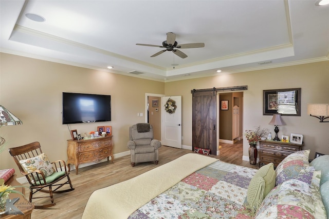 bedroom featuring light hardwood / wood-style floors, a raised ceiling, and a barn door