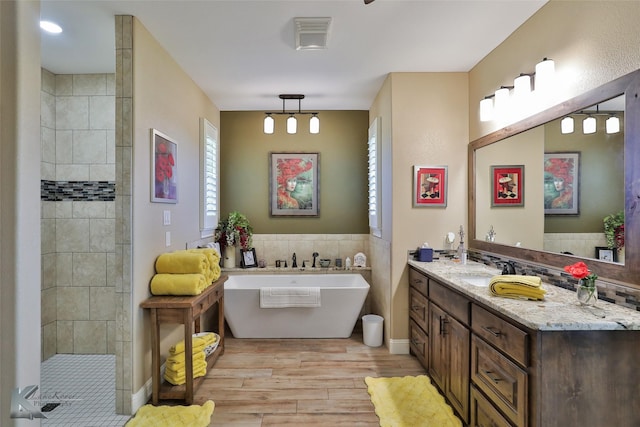 bathroom featuring hardwood / wood-style flooring, vanity, plus walk in shower, and tile walls