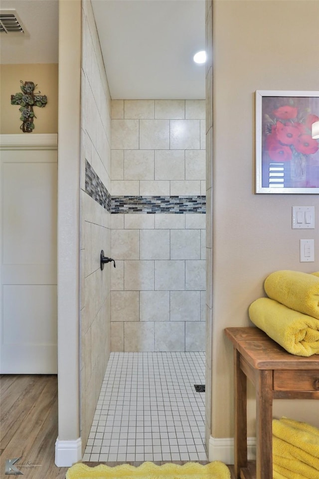 bathroom with wood-type flooring and a tile shower