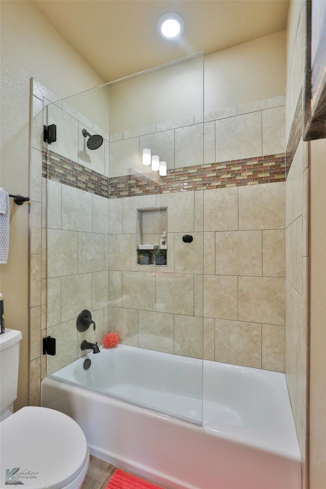 bathroom with tiled shower / bath combo and toilet