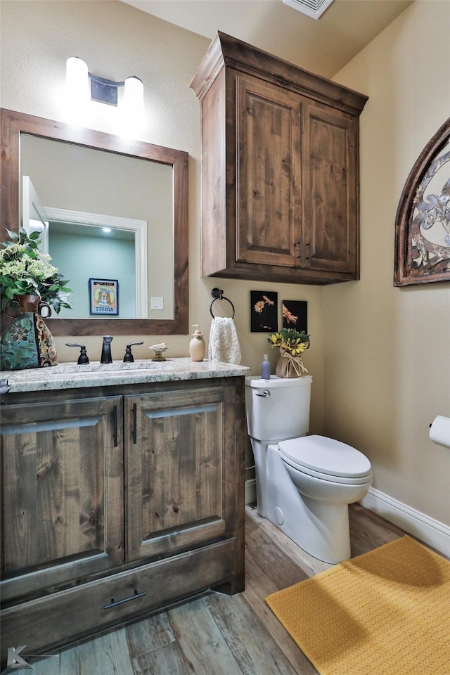 bathroom with vanity, toilet, and hardwood / wood-style floors